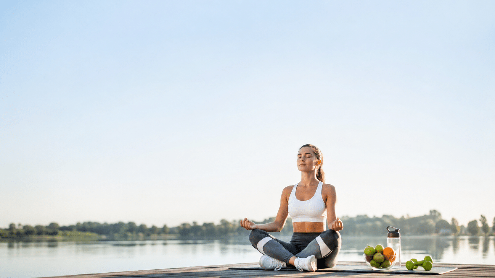 Donna che medita all’aperto con alimenti sani e attrezzatura fitness per uno stile di vita sano