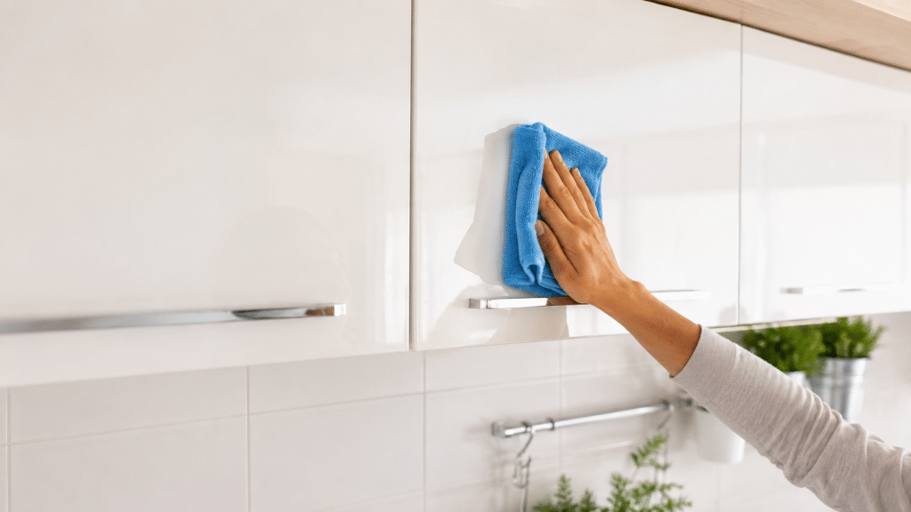 Cleaning kitchen doors with a microfiber cloth on modern furniture