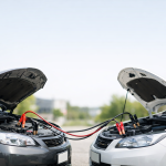 Auto con cofano aperto collegate con cavi per avviare un’auto con batteria scarica