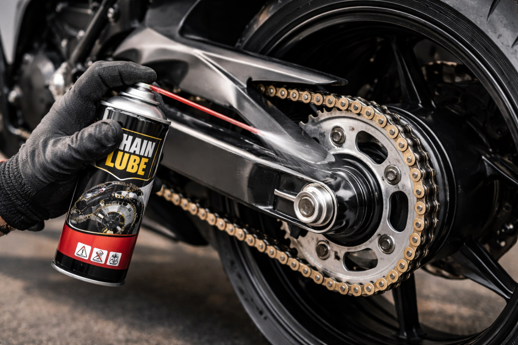 Motociclista che lubrifica la catena della moto con spray lubrificante durante la manutenzione.