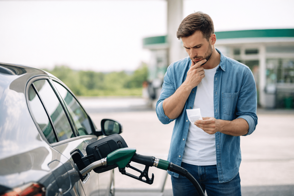 Uomo alla stazione di servizio controlla il costo del carburante durante il rifornimento