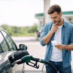 Man at gas station checks fuel cost while refueling