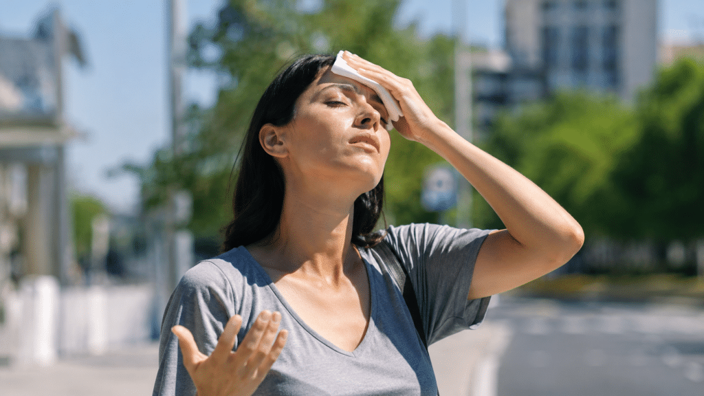 Persona affaticata dal caldo estivo con espressione stanca durante una giornata molto calda.